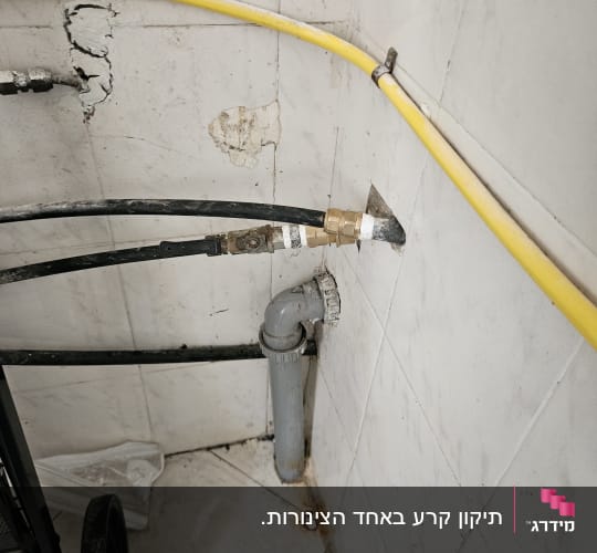 צינורות וחיבורים בפינת חדר עם קיר לבן